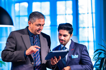 Indian businessmen collaborating on tablet for project planning in professional office space