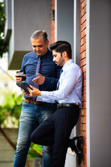 Indian business professionals with tablet collaborating outside modern corporate building