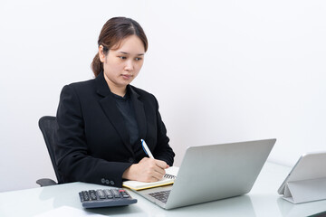 Asian businesswoman working on laptop computer, reading financial document report in office. Accountant, entrepreneur, manager. Businesswoman doing document using laptop computer.