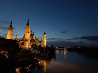 Obraz premium Basílica del Pilar iluminada al anochecer sobre el río Ebro