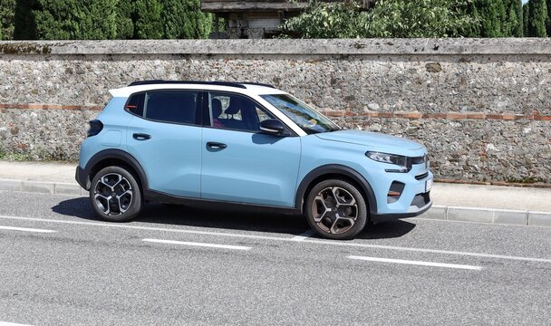 Udine, Italy. July 27, 2025. New blue Citroen C3 at the roadside with stone wall on behind.