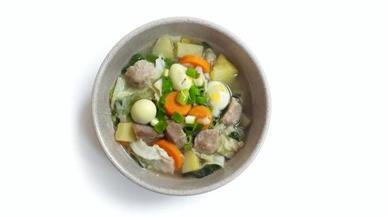 Sayur sop or vegetable soup, is an Indonesian food served on brown bowl. Isolated on white background. Food presentation photography