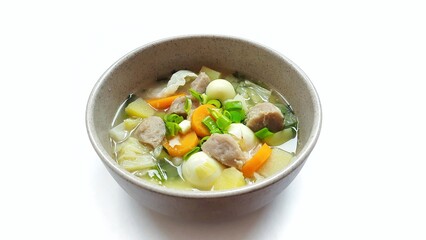 Sayur sop or vegetable soup, is an Indonesian food served on brown bowl. Isolated on white background. Food presentation photography