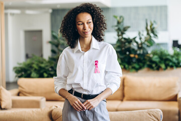 Young businesswoman wearing pink ribbon supporting breast cancer awareness month