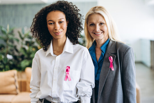 Two businesswomen wearing pink ribbons showing support for breast cancer awareness