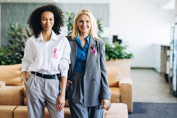 Businesswomen wearing pink ribbons showing support for breast cancer awareness