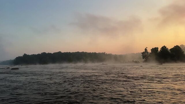 Wide right panning shot of the James River (Pony Pasture) during a misty summer sunrise is Richmond, Virginia