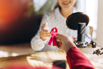 Radio host receiving pink ribbon for breast cancer awareness during podcast recording