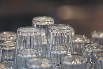 Stacked clear glass cups arranged on a surface in a cafe during the afternoon, ready for customers to use