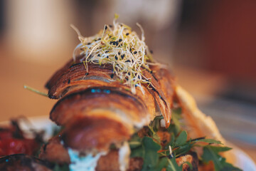 Delicious croissant sandwich with fresh sprouts and vegetables served in a cozy cafe during lunch hours