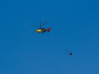 A firefighting helicopter carrying water to a forest fire