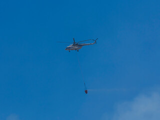 A firefighting helicopter carrying water to a forest fire