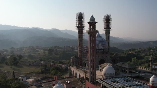 Panoramic drone view of a large mosque under construction in Kolti, Azad Kashmir, nestled amidst rolling hills. Gulhar sharif mosque.