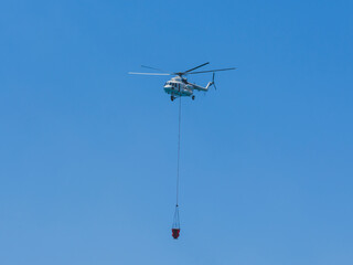 A firefighting helicopter carrying water to a forest fire
