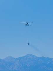 A firefighting helicopter carrying water to a forest fire