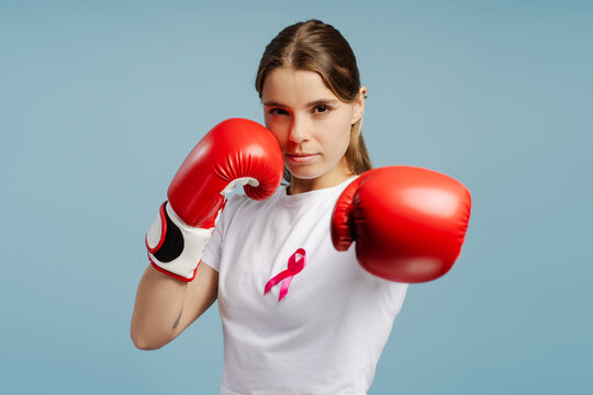 Young woman wearing boxing gloves and pink ribbon is fighting breast cancer
