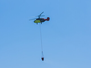 A firefighting helicopter carrying water to a forest fire