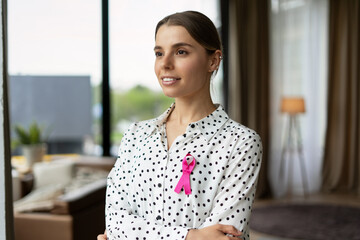 Businesswoman wearing pink ribbon showing support for breast cancer awareness