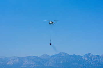 A firefighting helicopter carrying water to a forest fire