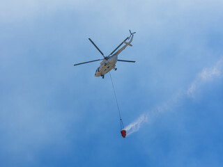A firefighting helicopter carrying water to a forest fire