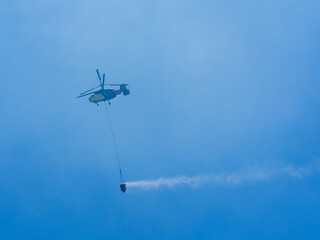 A firefighting helicopter carrying water to a forest fire