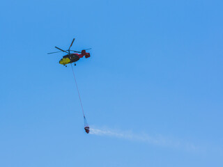 A firefighting helicopter carrying water to a forest fire