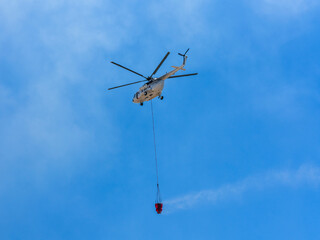 A firefighting helicopter carrying water to a forest fire