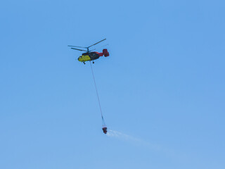 A firefighting helicopter carrying water to a forest fire