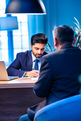 Young Indian professionals seal business deal with handshake in modern office setting
