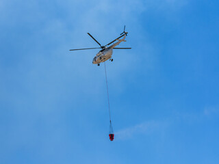 A firefighting helicopter carrying water to a forest fire