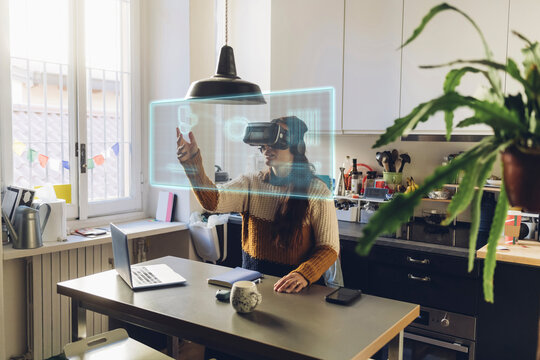 Woman wearing VR glasses touching transparent screen at home