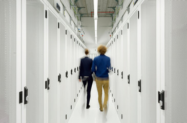 Young engineers walking in server room at data center