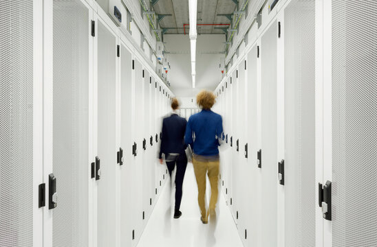 Young engineers walking in server room at data center