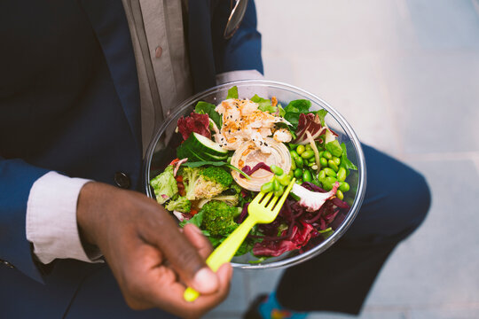 Businessman holding fork and having bowl of salad