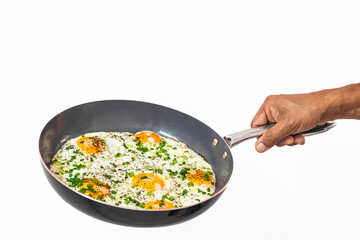 Male hand holding a stainless steel pan with fried eggs, sunny-side up eggs