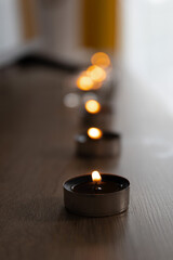 Tea light candles on wooden surface with bokeh effect, indoor setting, soft focus photography for relaxation concepts
