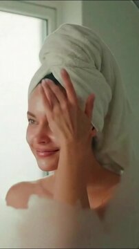 Woman Applying Moisturizer to Glowing Skin in Bathroom verticle video