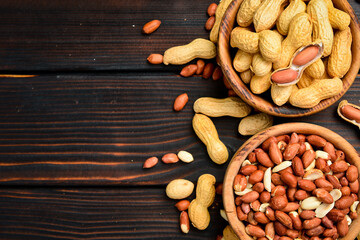 Two wooden bowls with peeled peanuts and peanuts in the shell. Nuts close-up.