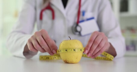 Female doctor measures apple circumference with measuring tape in medical office. Concept of nutrition with diet or health examination hangs around - Powered by Adobe