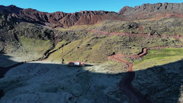 Drone video of a remote lodge from Andean loges, near vinicunca perus rainbow mountain. The logde is located between mountains surrounding with frost in the morning sun.