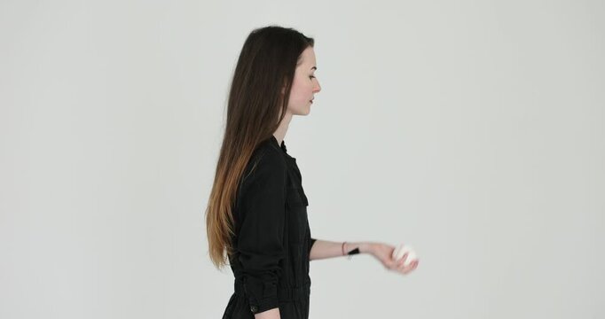 Young woman tossing tennis ball into air during pause. Blonde athlete raises arm launching ball in upward arc advertising sports item slow motion