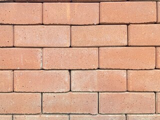 Obraz premium Brick Wall, The image shows a close-up of a brick wall constructed with light reddish-brown bricks, arranged in a staggered pattern. The bricks have a rough, textured surface.