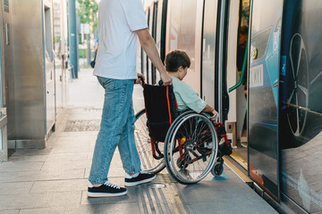 Boy in a wheelchair entering train at metro station with the help of an adult, urban transport lifestyle real life concept
