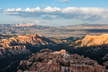 A scenic view of Bryce Canyon National Park, showcasing its unique hoodoo rock formations and vast landscape under a partly cloudy sky.