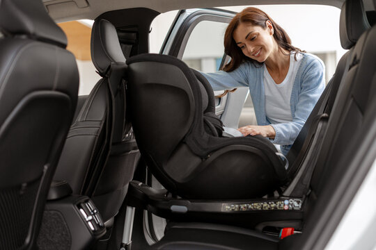 Mother Installing Baby Car Seat in Vehicle