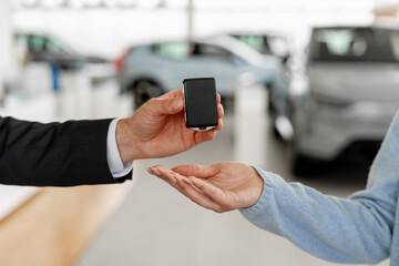 Car salesman giving car keys to a client in a dealership