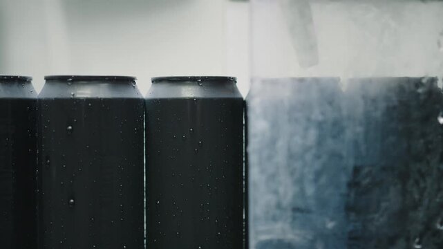 Black aluminum beverage cans glistening with condensation, revealing water droplets forming across surface while chilling and cooling down in dark professional setting