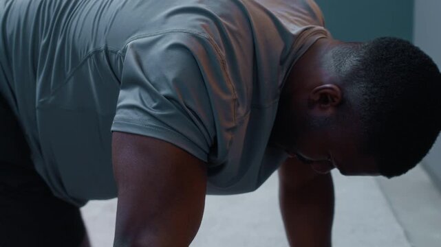 Close up of focused African American man wearing house arrest ankle bracelet doing mountain climbers while exercising at home, cultivating positive habits on probation