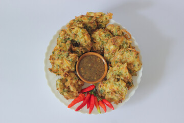 Bakwan or Vegetable fritters with peanut sauce and red chili. Vegetable fritters are fried snacks made from a mixture of vegetables and flour batter, usually fried until crispy. Bala Bala or Ote Ote.