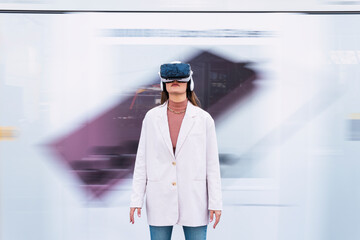 Businesswoman wearing virtual reality simulator standing in front of wall
